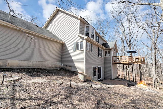 view of property exterior featuring a deck and roof with shingles