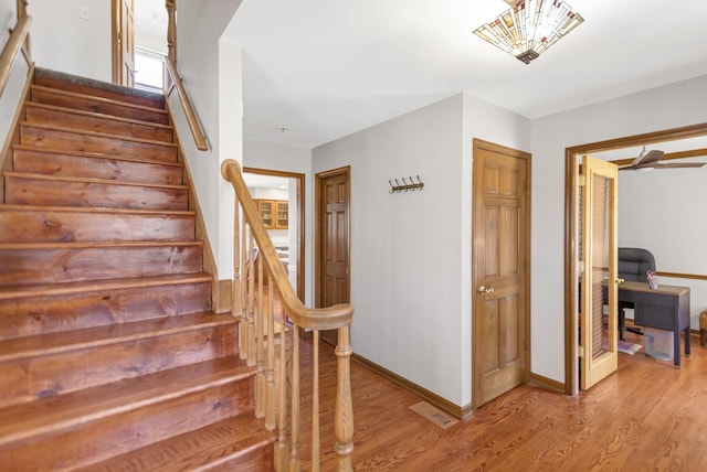 stairway featuring visible vents, baseboards, and wood finished floors