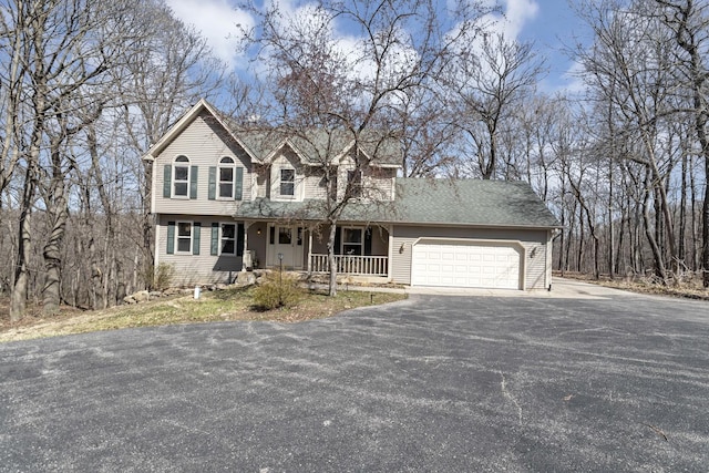 view of front of property featuring a porch, aphalt driveway, and a garage