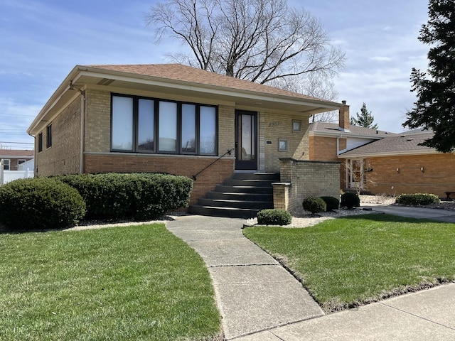 bungalow-style home featuring a chimney, a front yard, and brick siding