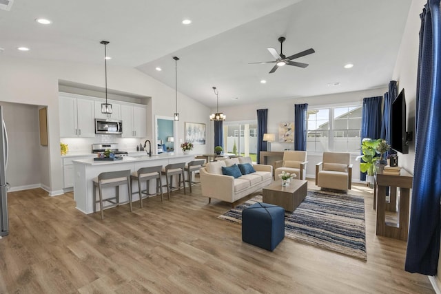 6367 Jasmine Ave, Portage, IN 46368 - living area featuring high vaulted ceiling, baseboards, light wood-style flooring, and ceiling fan with notable chandelier