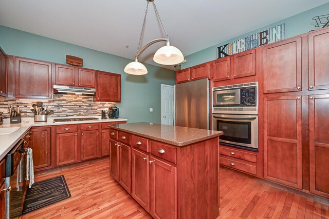 2136 Yale Cir, Hoffman Estates, IL 60192 - kitchen with a center island, light wood-type flooring, appliances with stainless steel finishes, under cabinet range hood, and decorative backsplash