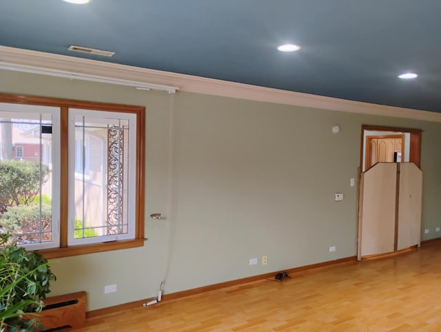 unfurnished room with light wood-style flooring, baseboards, ornamental molding, and visible vents