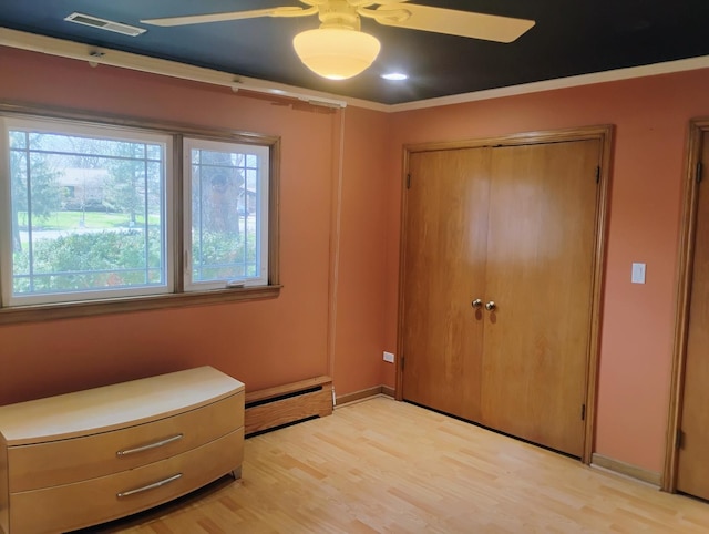 unfurnished bedroom featuring visible vents, multiple windows, light wood-style floors, and baseboard heating