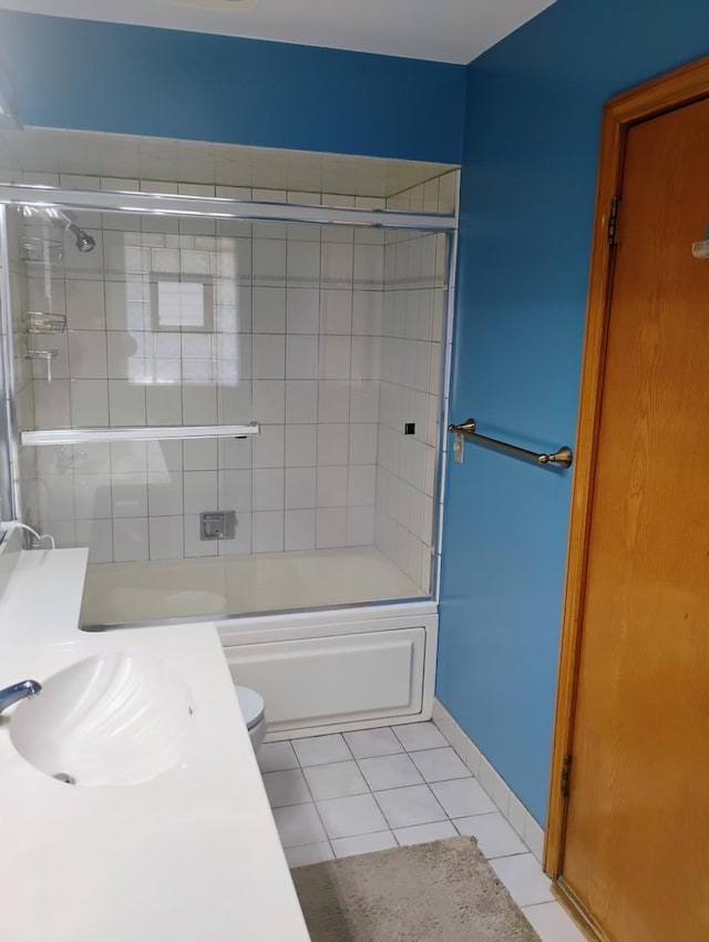 bathroom featuring toilet, tile patterned floors, a sink, and bath / shower combo with glass door