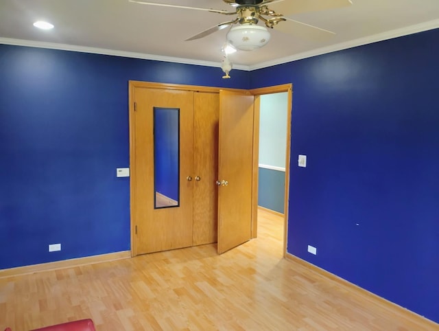 unfurnished bedroom featuring light wood-style floors, a closet, ornamental molding, a ceiling fan, and baseboards
