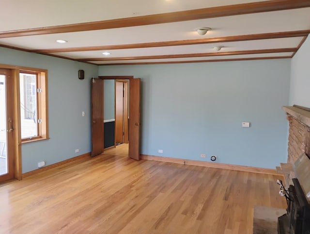 unfurnished living room with beam ceiling, baseboards, light wood finished floors, and a fireplace