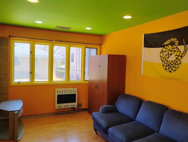living area featuring wood finished floors, recessed lighting, visible vents, and heating unit