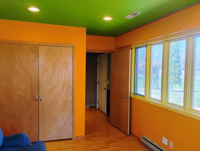 bedroom with recessed lighting, light wood-type flooring, visible vents, and a baseboard radiator