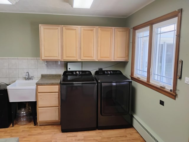 laundry area with baseboard heating, light wood-style floors, cabinet space, washer and dryer, and a sink