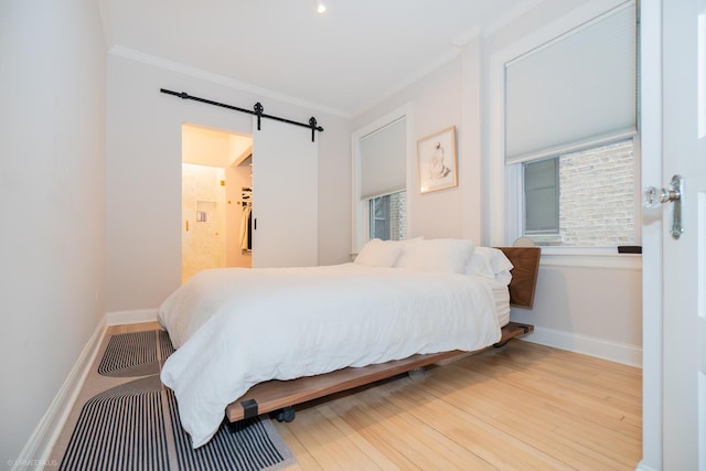 bedroom featuring crown molding, a barn door, baseboards, and wood finished floors
