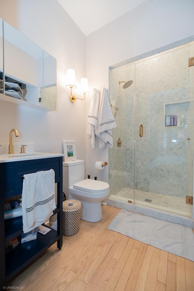 full bath featuring wood finished floors, a stall shower, toilet, and vanity