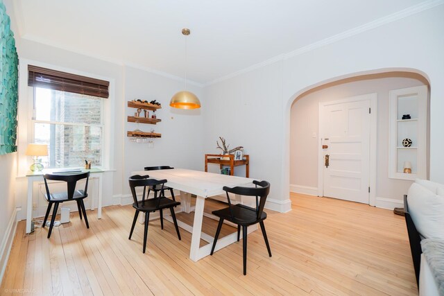 dining room with arched walkways, light wood-style flooring, ornamental molding, and baseboards