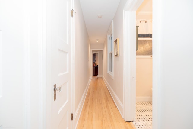 hallway featuring light wood-style flooring and baseboards