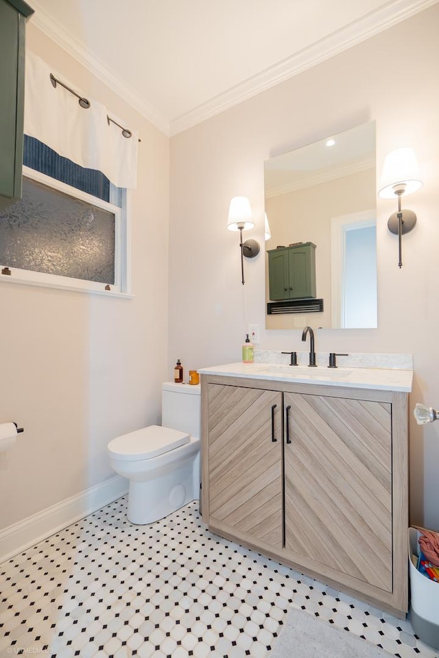 bathroom featuring toilet, crown molding, baseboards, and vanity
