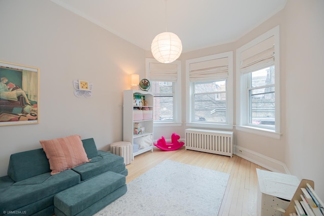 living area with radiator, wood finished floors, and baseboards
