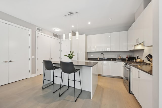 1701 W Webster Ave Unit 512, Chicago, IL 60614 - kitchen with white cabinets, stainless steel range with gas cooktop, dark countertops, and visible vents