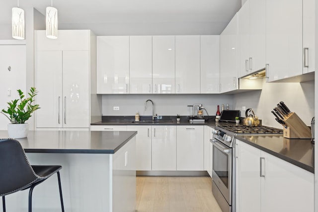 1701 W Webster Ave Unit 512, Chicago, IL 60614 - kitchen featuring white cabinets, gas range, light wood-type flooring, dark countertops, and under cabinet range hood