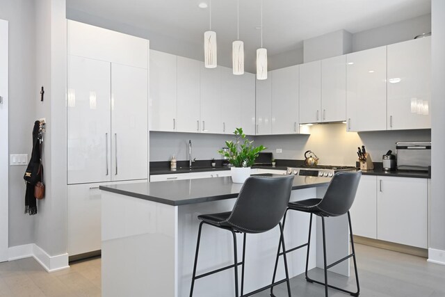 1701 W Webster Ave Unit 512, Chicago, IL 60614 - kitchen featuring hanging light fixtures, a center island, dark countertops, a kitchen bar, and white cabinetry