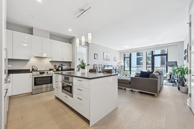 1701 W Webster Ave Unit 512, Chicago, IL 60614 - kitchen with hanging light fixtures, white cabinets, dark countertops, light wood finished floors, and stainless steel appliances