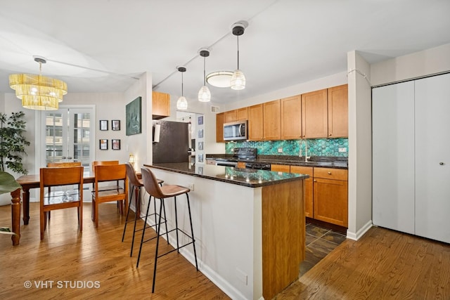 222 E Pearson St Unit 409, Chicago, IL 60611 - kitchen with stainless steel appliances, dark wood-style floors, decorative backsplash, and an inviting chandelier