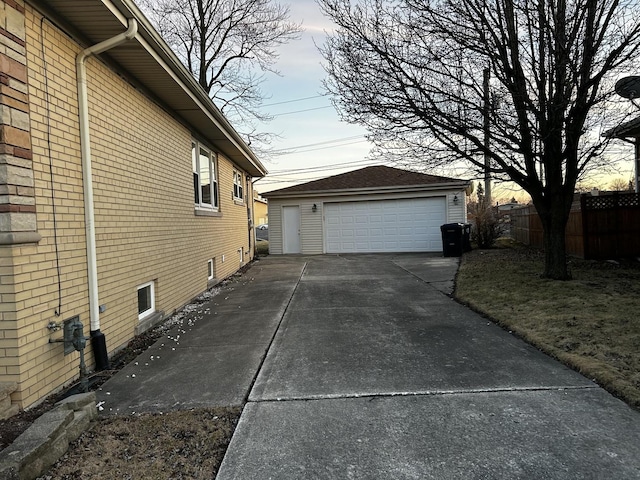 view of side of property featuring brick siding, fence, an outbuilding, and a garage
