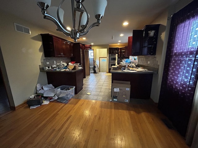 kitchen featuring stainless steel appliances, an inviting chandelier, visible vents, light wood-style floors, and decorative backsplash