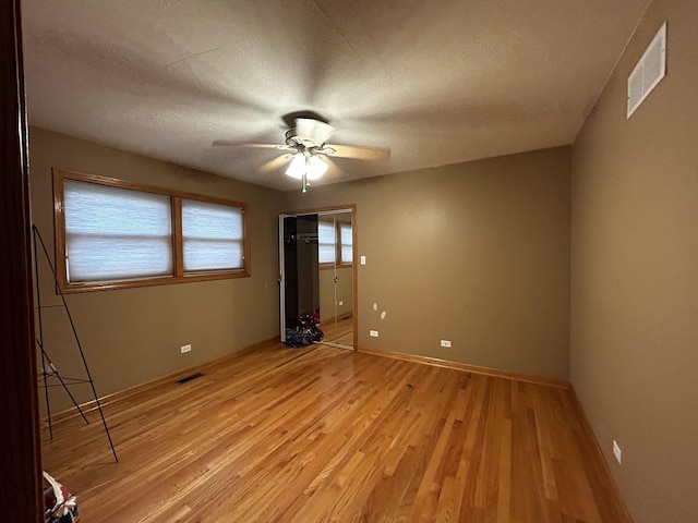 empty room featuring baseboards, light wood-style flooring, visible vents, and ceiling fan