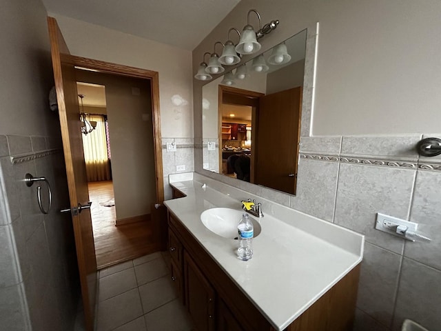 bathroom with tile walls, tile patterned flooring, vanity, and wainscoting