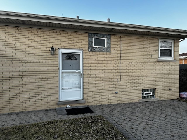 property entrance featuring brick siding and a patio