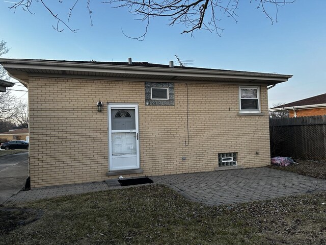 rear view of property with fence, brick siding, and a patio