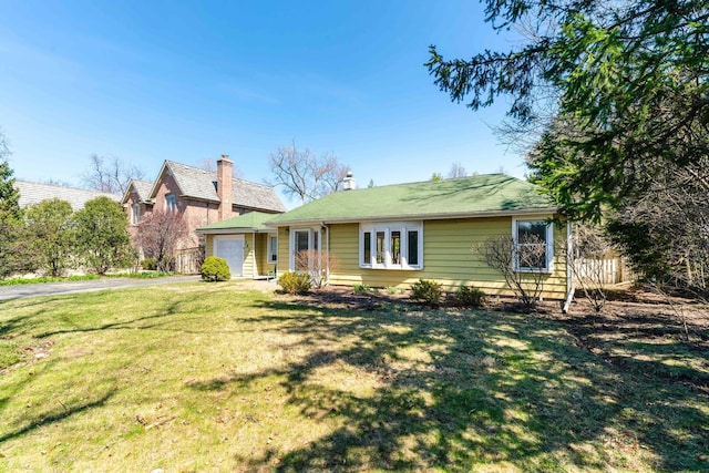 view of front of property featuring aphalt driveway, an attached garage, and a front yard