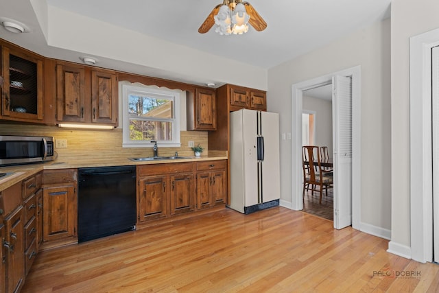 kitchen featuring dishwasher, a sink, light countertops, freestanding refrigerator, and stainless steel microwave