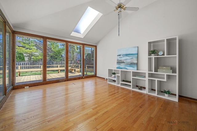 unfurnished living room with baseboards, a ceiling fan, a skylight, high vaulted ceiling, and wood finished floors