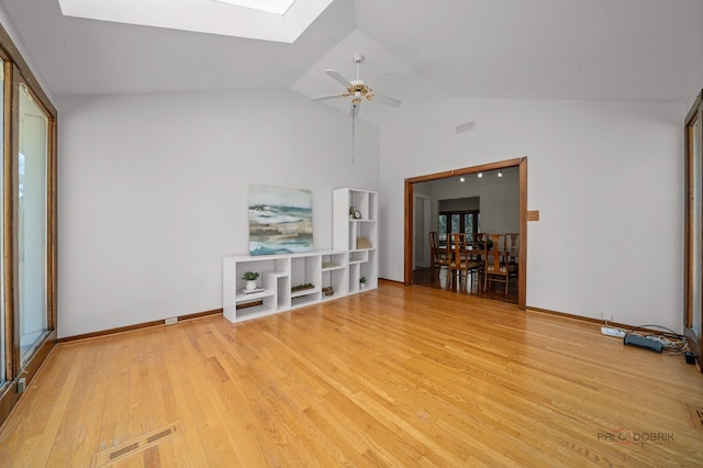 spare room featuring light wood-style flooring, a ceiling fan, visible vents, and lofted ceiling with skylight