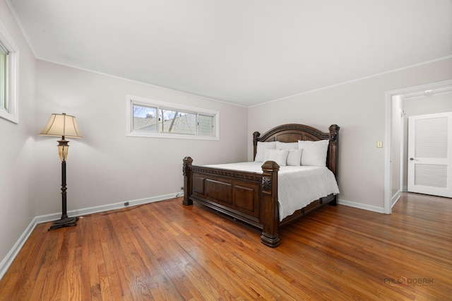 bedroom featuring crown molding, wood-type flooring, and baseboards