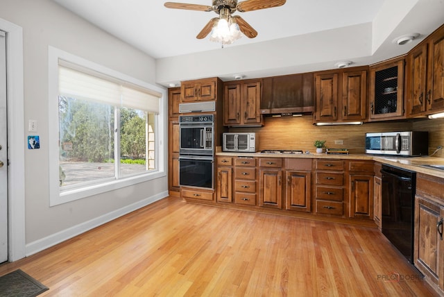 kitchen with baseboards, a ceiling fan, decorative backsplash, light wood finished floors, and black appliances