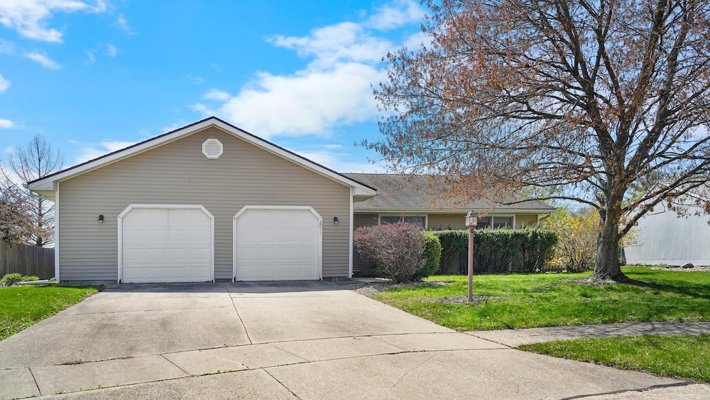 ranch-style home with an attached garage, a front lawn, and concrete driveway