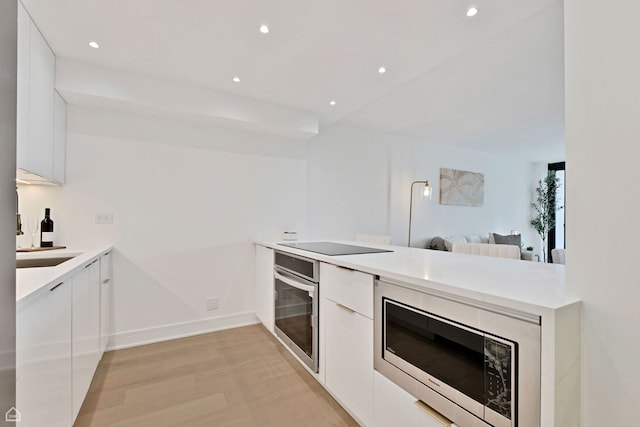 1560 N Sandburg Ter Unit 1011J, Chicago, IL 60610 - kitchen featuring a peninsula, appliances with stainless steel finishes, modern cabinets, and white cabinetry