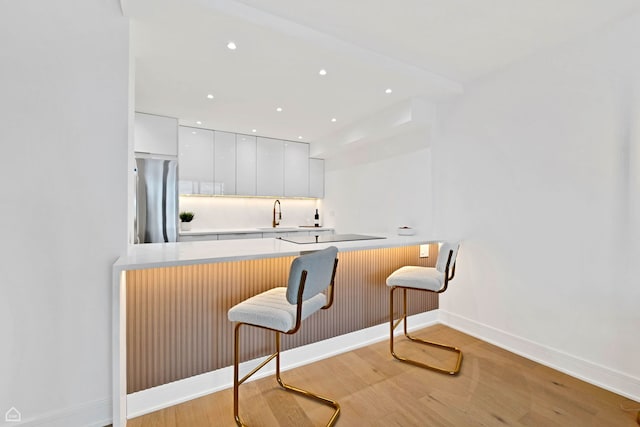 1560 N Sandburg Ter Unit 1011J, Chicago, IL 60610 - kitchen featuring modern cabinets, freestanding refrigerator, a kitchen breakfast bar, light wood finished floors, and white cabinetry
