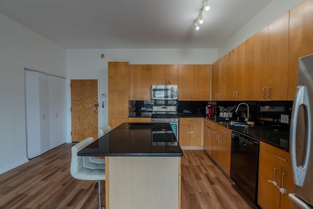 kitchen featuring decorative backsplash, appliances with stainless steel finishes, wood finished floors, and a sink