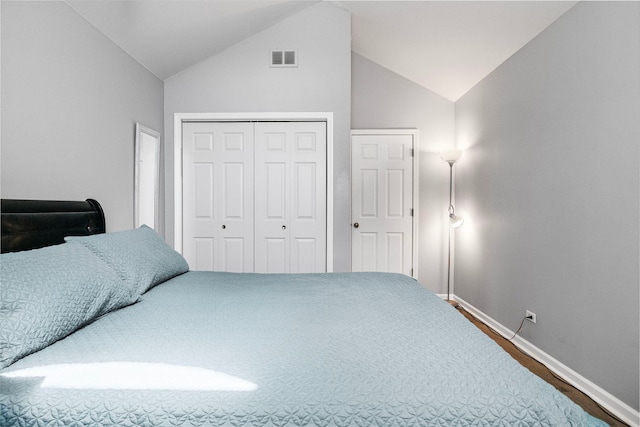 bedroom with a closet, baseboards, visible vents, lofted ceiling, and wood finished floors