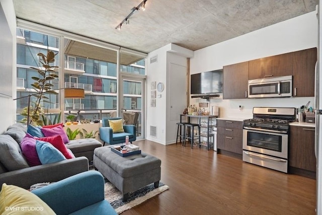 living area with dark wood finished floors, rail lighting, a wealth of natural light, and visible vents