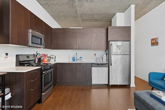 kitchen with stainless steel appliances, dark wood-style floors, dark brown cabinets, modern cabinets, and light countertops