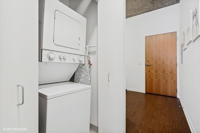 laundry area featuring baseboards, wood finished floors, stacked washer / dryer, and laundry area