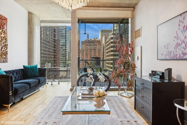 living room with a city view, a notable chandelier, wood finished floors, and floor to ceiling windows