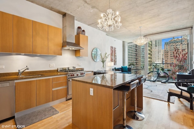 kitchen with a notable chandelier, light wood-type flooring, wall chimney exhaust hood, dishwashing machine, and high end stove