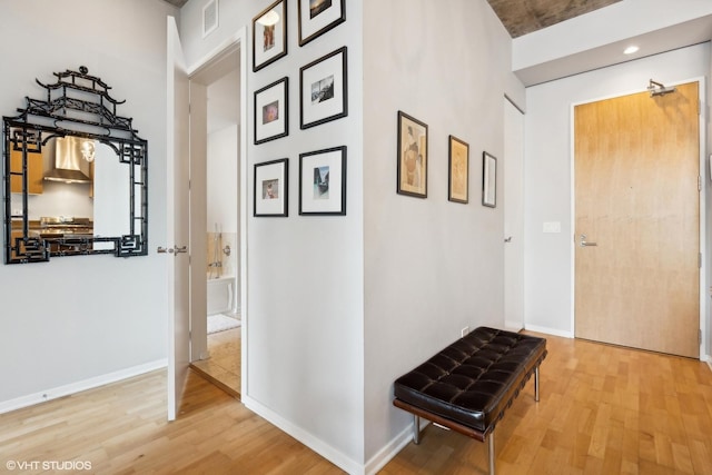 corridor featuring wood finished floors, baseboards, and visible vents