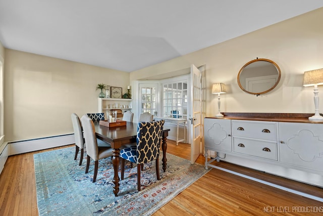 dining area featuring a baseboard heating unit and light wood-style floors