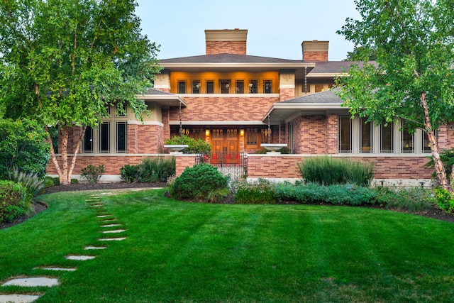 rear view of property with a yard, brick siding, and a chimney